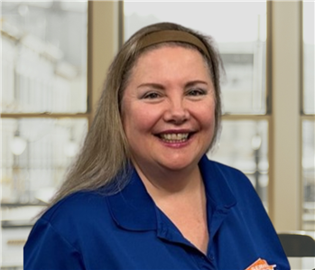 Woman with blonde hair and a blue shirt with a servpro logo on it