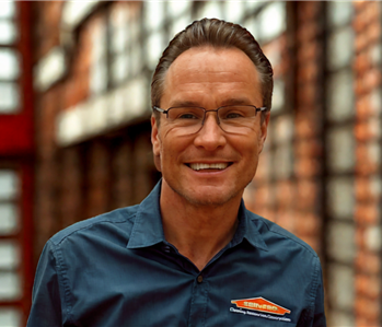 smiling man with brown hair and a laid shirt on