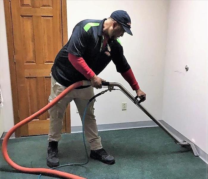 man in Servpro shirt cleaning a carpet