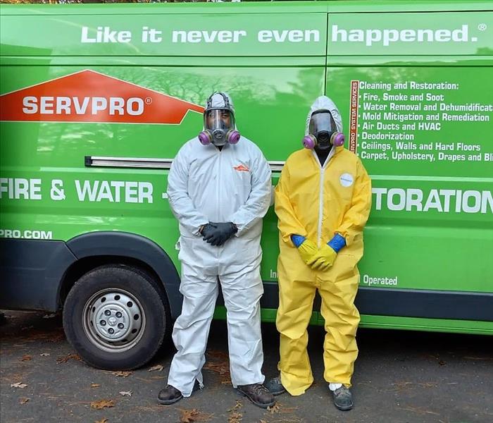 2 servpro employees in front of a van in biohazard protective clothing